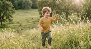 A high-quality, editorial-style photograph of a healthy, happy preschooler playing outdoors in a sun